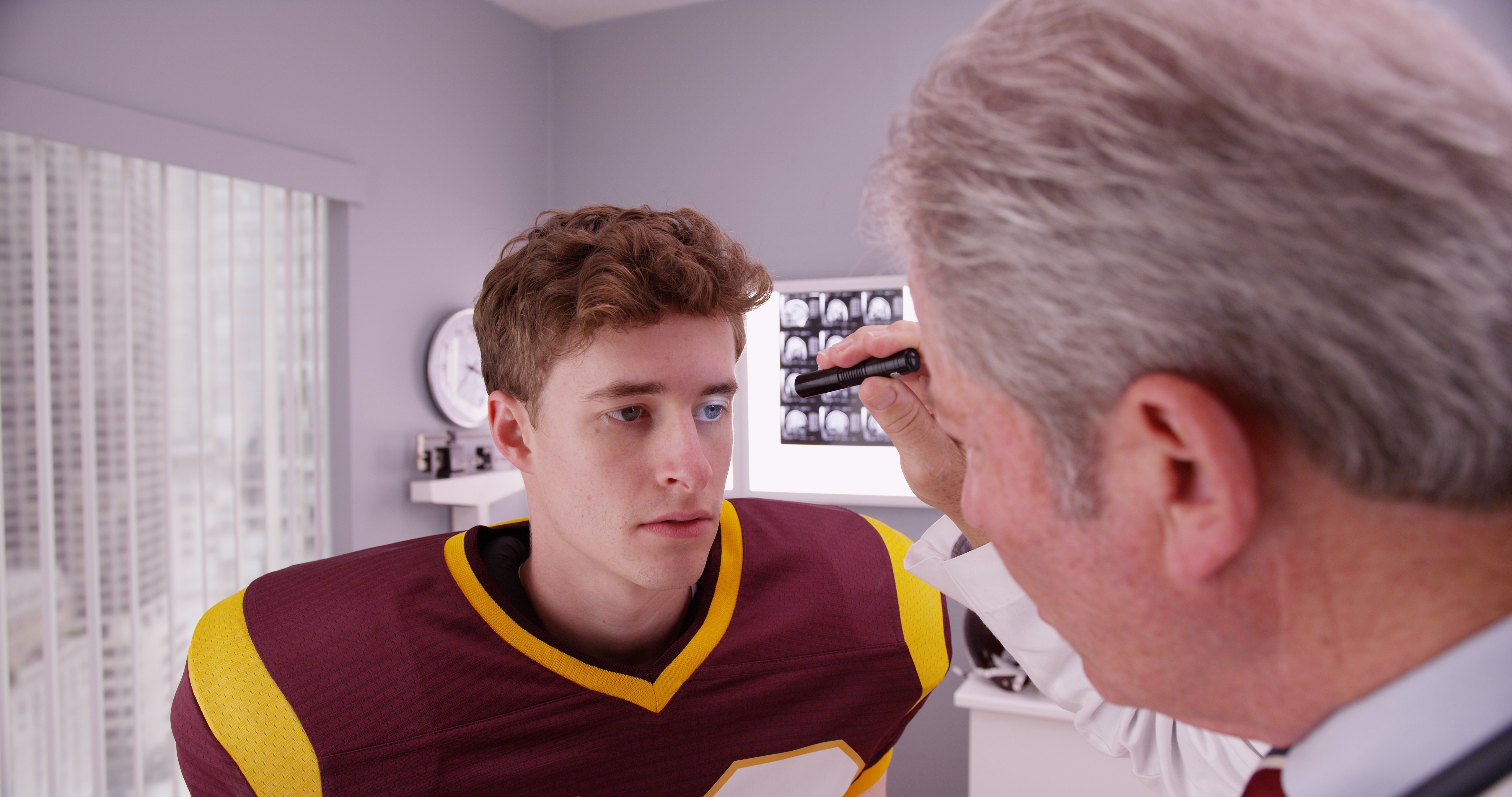 storyblocks-mid-aged-doctor-examining-football-player-after-concussion_B04bXlpja_m